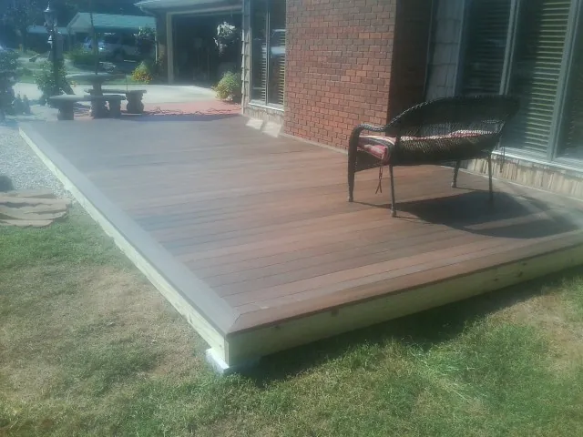 New wood deck and wicker chair beside a brick house in Bastrop