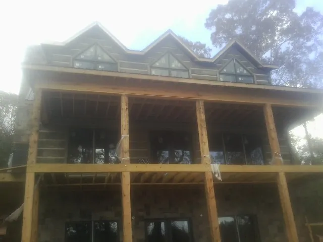Dormers and porch framing on a large log home under construction — Roof Coating work by our crew in Bastrop
