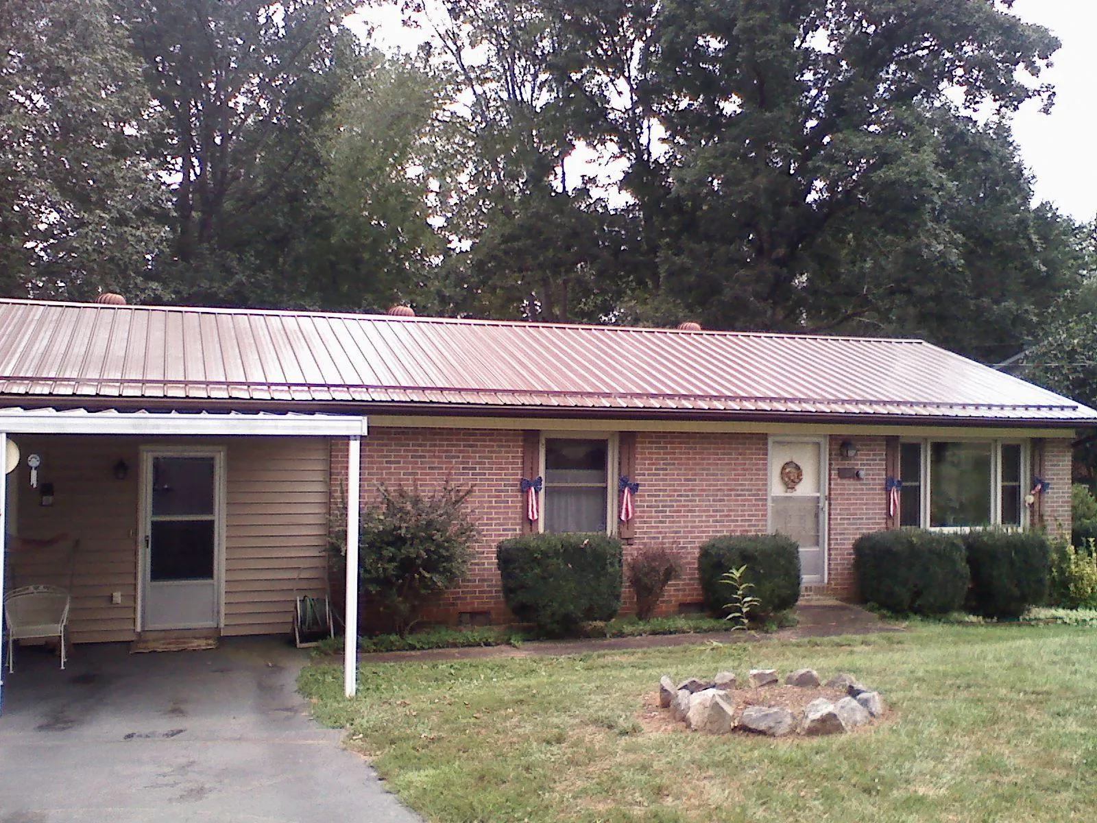 Bronze metal roof and carport on a brick ranch home — Roof Repair work by our crew in Bastrop
