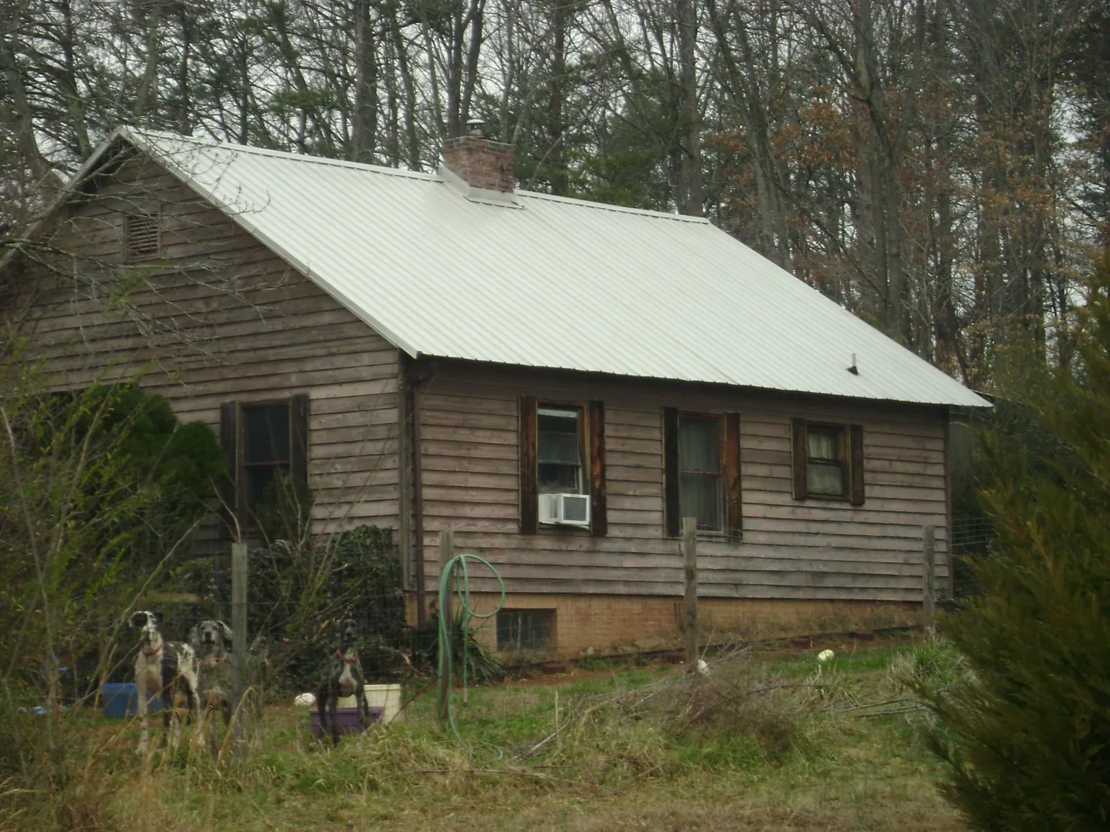 White metal roof on an old wood sided farmhouse, from a Metal Roof Installation job in Bastrop
